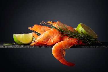 Biberiyeli karides ve siyah arka planda limon. Boşluğu kopyala.