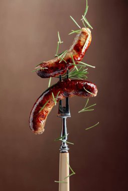 Biberiyeli ızgara Bavyera sosisi. Biberiye serpilmiş çatallı sosisler. Kahverengi arkaplan.