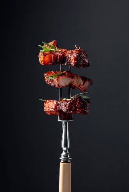 Izgara domuz göbeği ve çatallı biberiye. Siyah arkaplan.