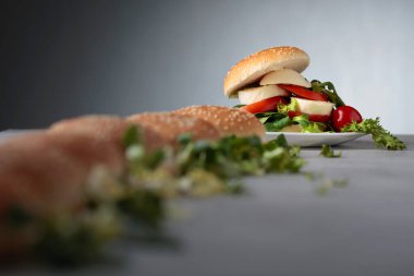 Mozzarella peyniri, domates ve yeşillik mutfak masasının üzerinde sandviç. Bun susam, peynir ve salata ile. Seçici odak. Kopya alanı.