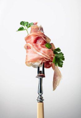 Çatalla maydanozlu ince dilimlenmiş jambon. Geleneksel İtalyan mutfağı.