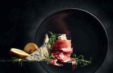 Geleneksel Akdeniz atıştırmalıkları. Prosciutto ya da İspanyol jamonu, mavi peynir, armut ve biberiye. Boşluğu kopyala.