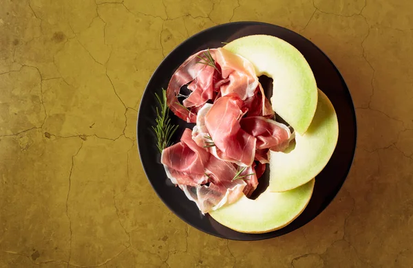 Prosciutto Mit Rosmarin Und Melone Auf Einem Schwarzen Teller Ansicht — Stockfoto