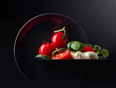 Siyah arka planda domates ve fesleğenli Mozzarella. Boşluğu kopyala.