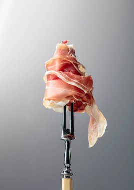 Çatalda ince dilimlenmiş prosciutto. Geleneksel İtalyan mutfağı.