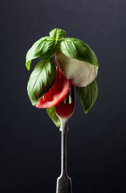 Siyah arka planda domates ve fesleğenli Mozzarella..