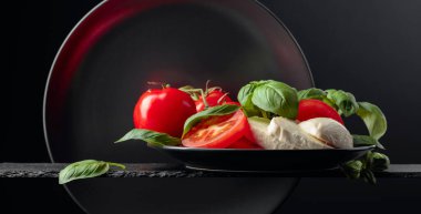 Siyah arka planda domates ve fesleğenli Mozzarella. Boşluğu kopyala.