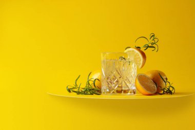 Sarı arka planda limonlu ve biberiyeli cin tonik kokteyli. Fotokopi alanı olan karbonatlı içecek.