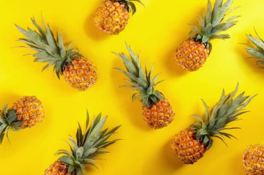 Sarı arka planda olgun ve sulu ananaslar..