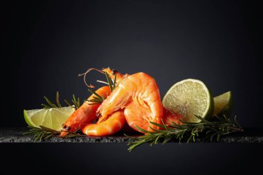 Biberiyeli karides ve siyah arka planda limon. Boşluğu kopyala.