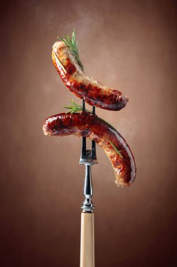 Izgara Bavyera sosisi ve çatalla biberiye. Kahverengi arkaplan.