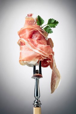 Çatalla maydanozlu ince dilimlenmiş jambon. Geleneksel İtalyan mutfağı.