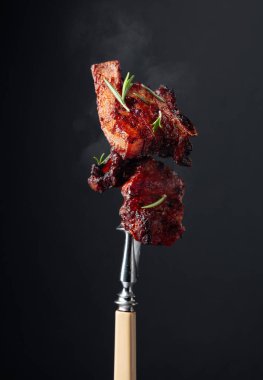 Izgara domuz göbeği ve çatallı biberiye. Siyah arkaplan.