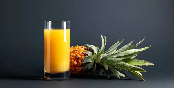 Fresh ripe pineapple and juice on a black background. Copy space.