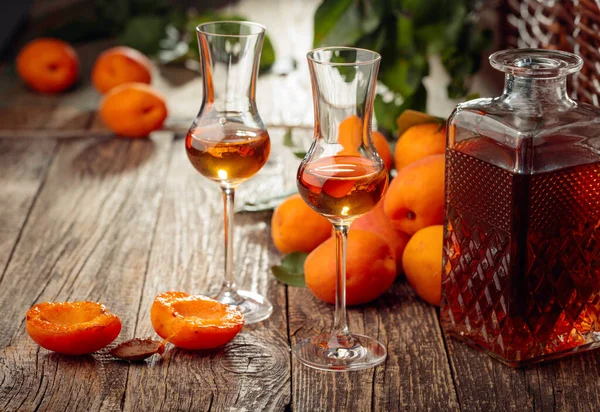 Apricot liquor and fresh apricots on a old wooden table. Wine and juicy fruits on a rustic background.