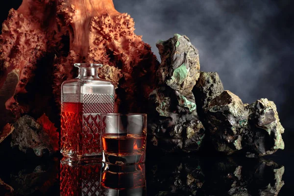 黑色反光背景下的玻璃杯和威士忌酒 背景上有石头和一棵枯树 复制空间 — 图库照片