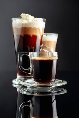 Espresso, latte macchiato ve siyah yansıtıcı arka planda İrlanda kahvesi..