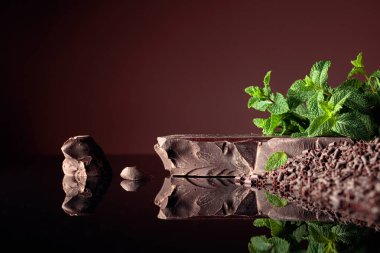 Siyah yansıtıcı arka planda naneli koyu acı çikolata ve çikolata parçaları. Boşluğu kopyala.