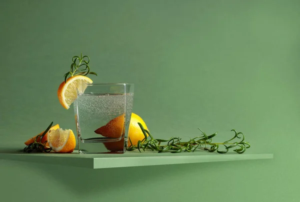 Carbonated drink with lemon and rosemary on a green background.  Copy space.