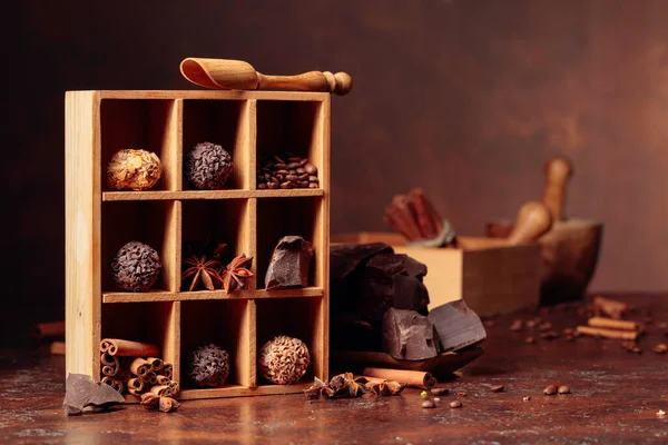 Chocolate truffles with broken pieces of chocolate and spices. Chocolate, cinnamon sticks, anise and coffee beans in wooden box. Copy cpace.