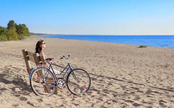 中年妇女骑自行车来到海滩 坐在长椅上休息 夏日明媚的夜晚 在海滩上 — 图库照片