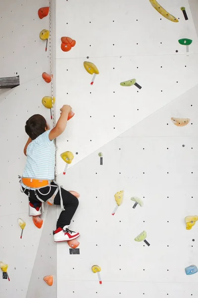 Child climbing on a high wall — Stock Photo, Image