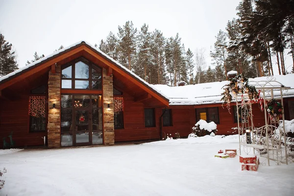 Casa de madera de invierno y un bosque de coníferas — Foto de Stock