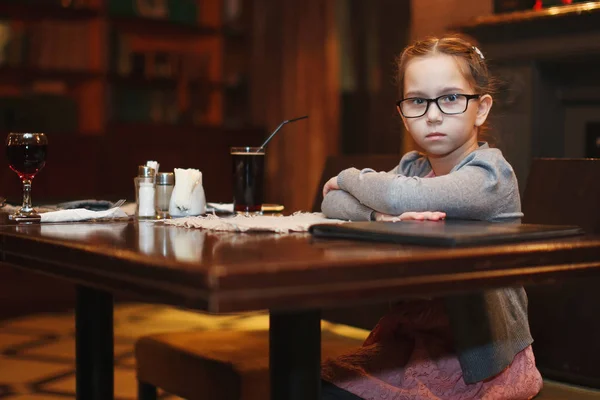 Schattig jong meisje in glazen in een café — Stockfoto