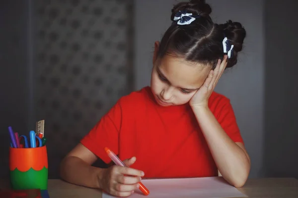 Meisje trekt een marker zittend aan tafel thuis — Stockfoto