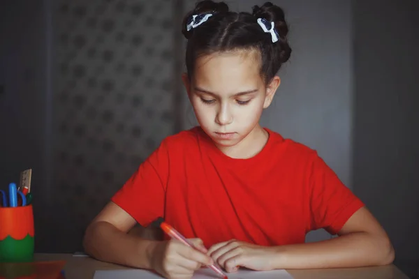 Meisje trekt een marker zittend aan tafel thuis — Stockfoto