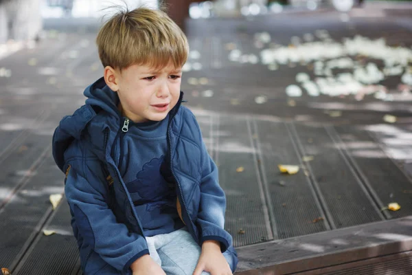 Küçük çocuk parkta otururken ağlıyor