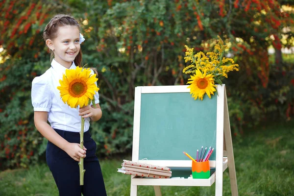 Schoolmeisje met een schoolbord in het park. — Stockfoto