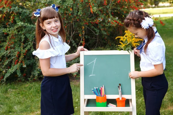 Schoolmeisjes met een schoolbord in het park. — Stockfoto
