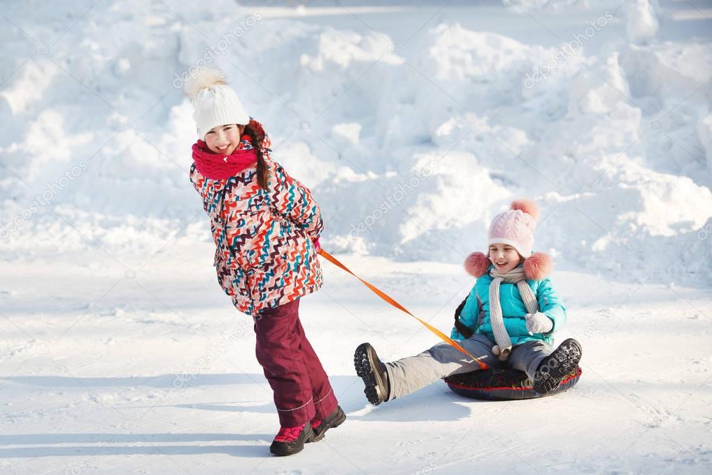 Happy little Girls slidding snow tubing