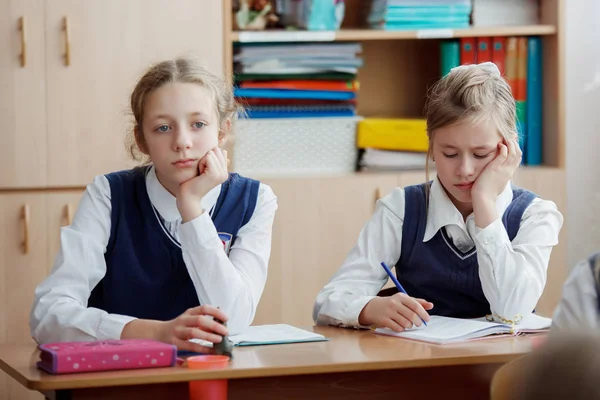 Basisschool leerlingen op een les in school schrijven in notitieboekjes — Stockfoto