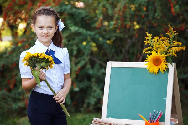 Schoolmeisje met een schoolbord in het park. — Stockfoto