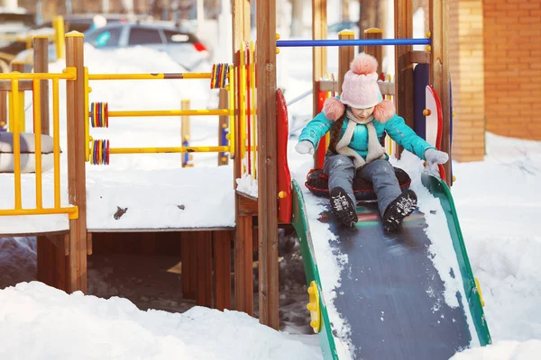 Happy cute dziewczynka slajdy w zimie — Zdjęcie stockowe