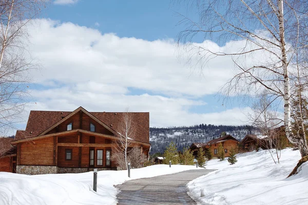 Vacaciones de invierno casa de madera en las montañas cubiertas de nieve y cielo azul — Foto de Stock