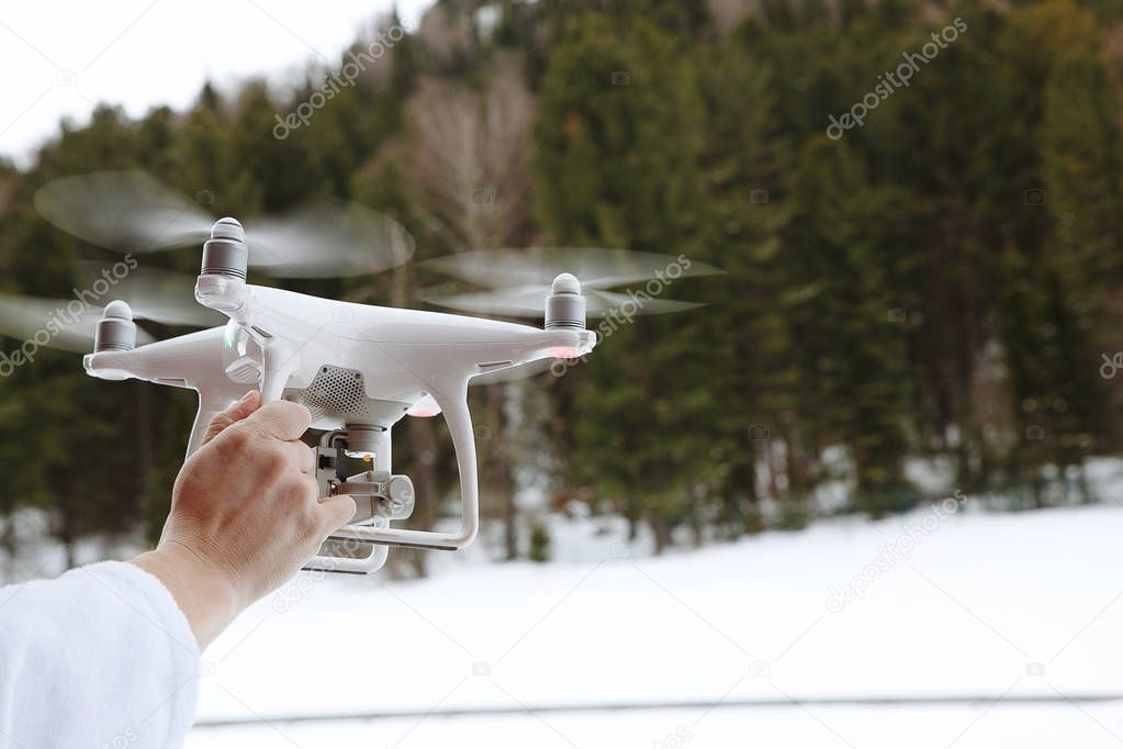 Quadrocopter, drone in flight against the background of a coniferous forest, in the mountains