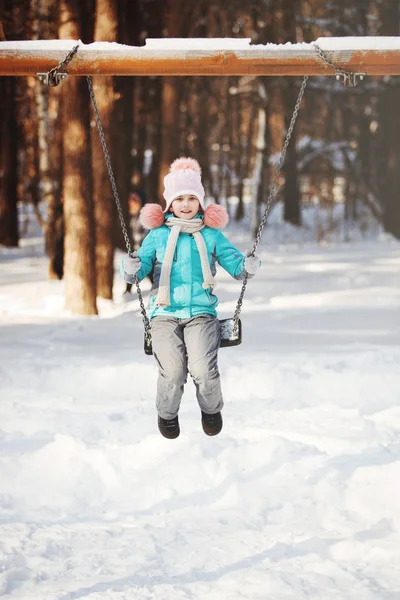 Adorable niña en un columpio en invierno — Foto de Stock