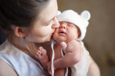 Güzel bir kadın kucağında yeni doğmuş bir bebeği tutuyor.