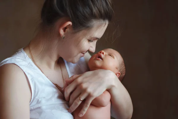 Pretty woman holding a newborn baby in her arms — Stock Photo, Image