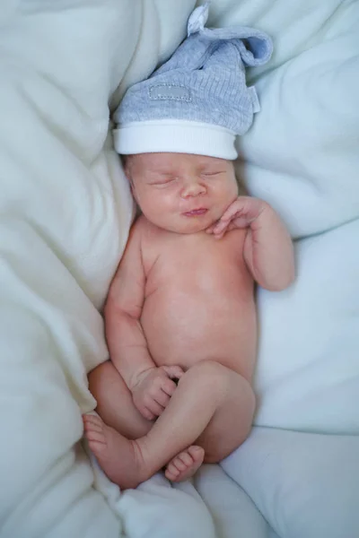 Спящий ребенок в синей шапке в кровати — стоковое фото