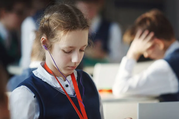 Eine Schülerin hört Musik über Kopfhörer und liest ein Buch — Stockfoto