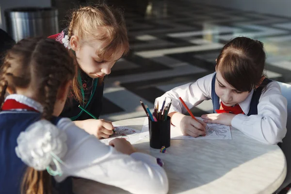 Школярі малюють кольоровими олівцями, сидячи за столом — стокове фото