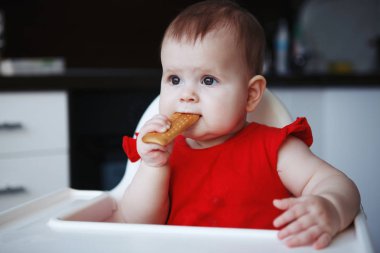 Bebek Kırmızı elbiseli bir çocuğun sandalyenin üstüne oturuyor