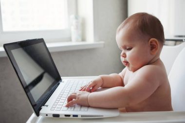 Bebek bir dizüstü bilgisayar ile beyaz bir sandalyesi oturur