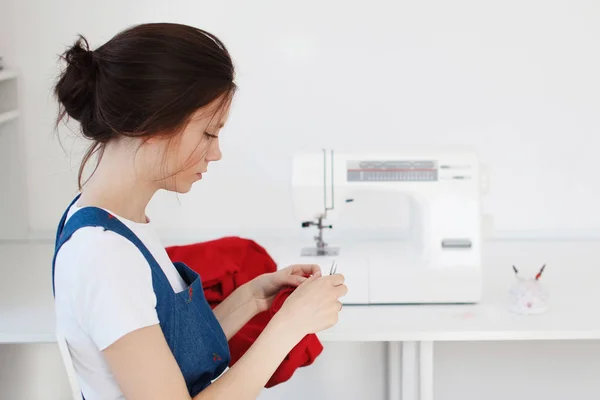 Симпатичная молодая девушка в синем платье пришивает швейную машинку . — стоковое фото