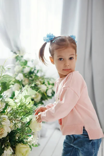 Stüdyoda yeşil çiçek bir buket pembe bir kazak, çekici sevimli küçük kız — Stok fotoğraf