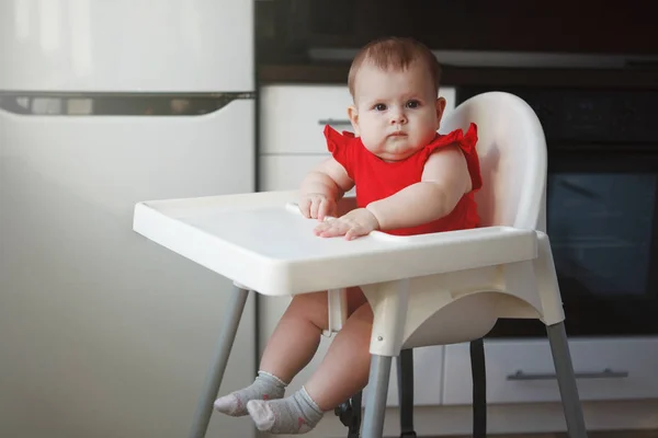 Egy piros ruha baba ül egy gyermek szék — Stock Fotó